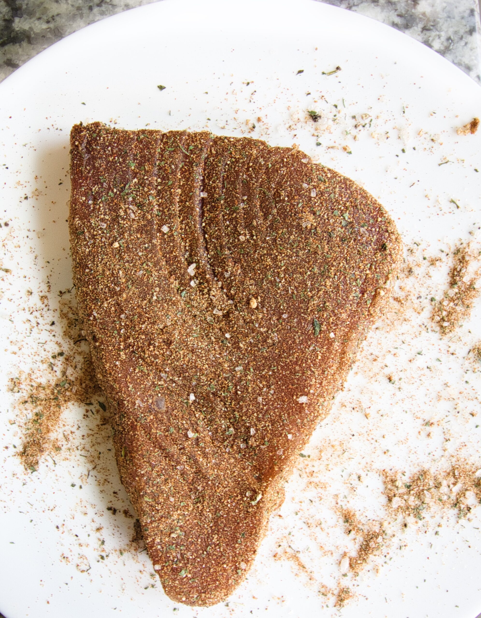 picure of a ahi tuna steak raw with seasoning all over it