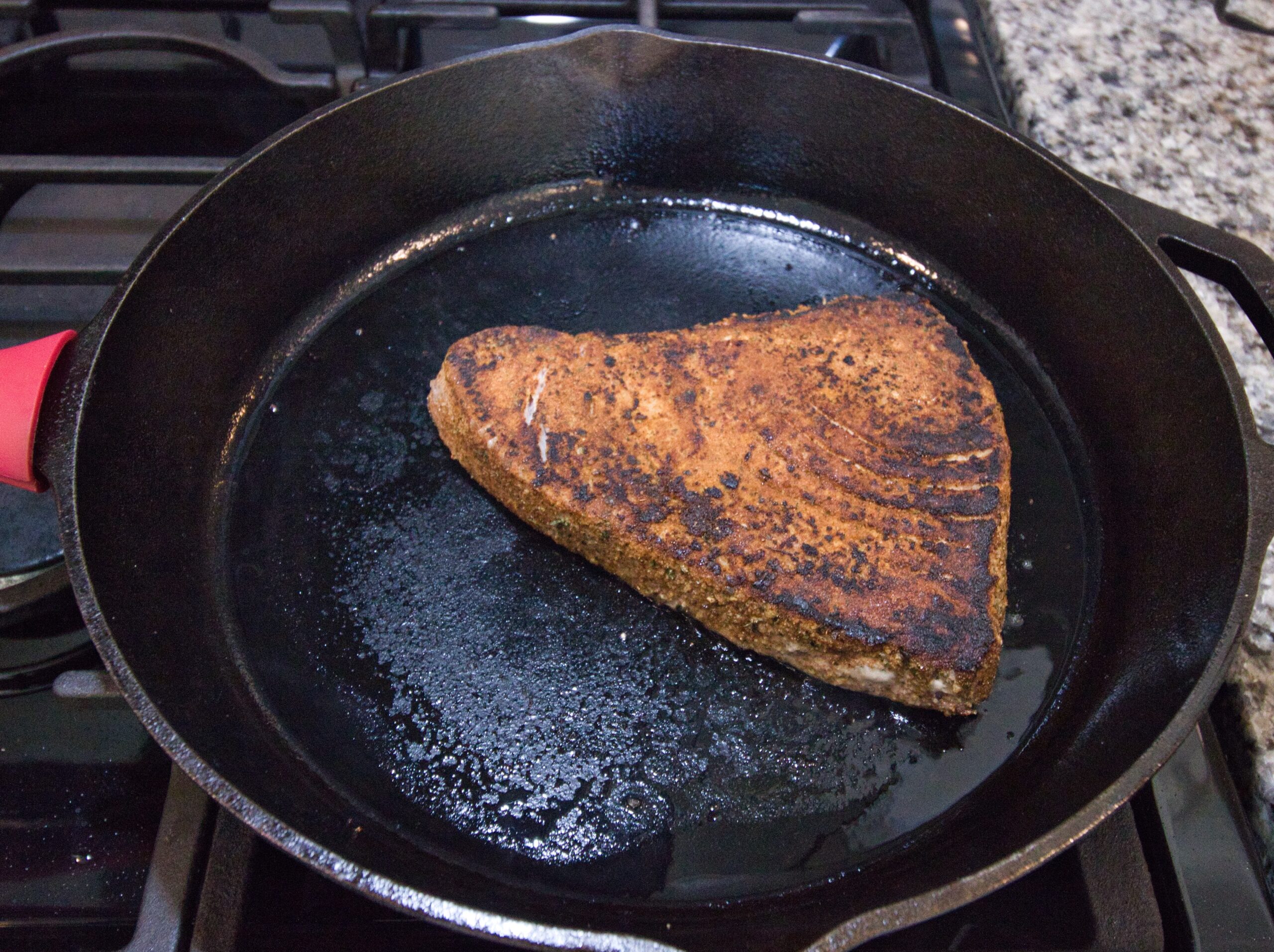 cooked ahi tuna steak in a hot cast iron pan on the stove 