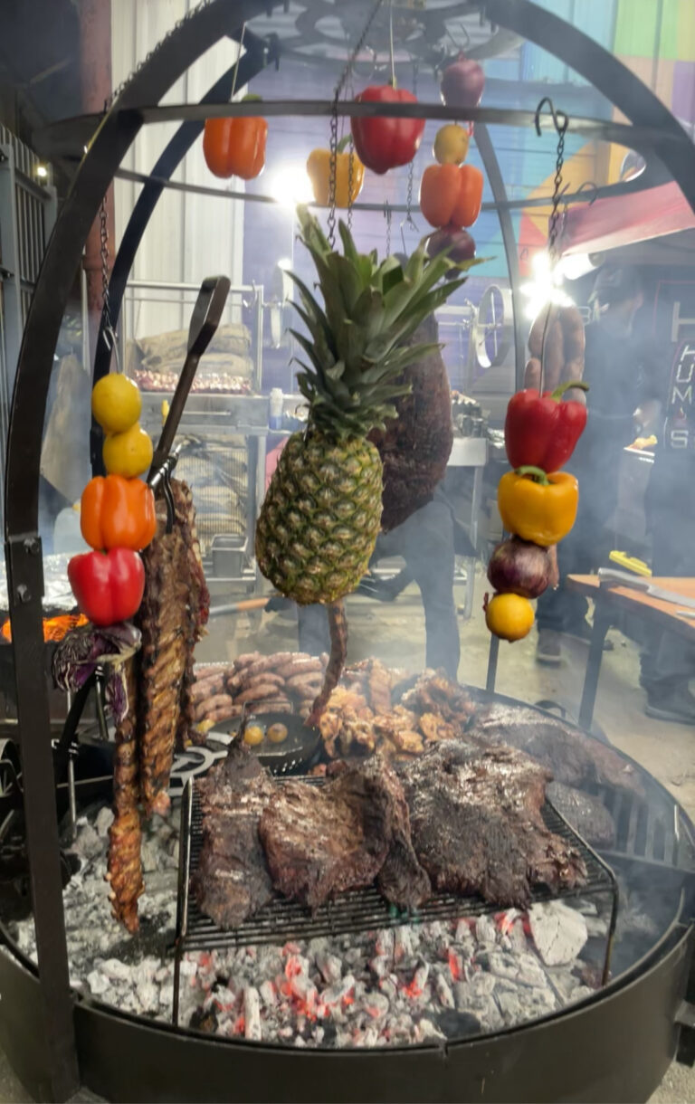 fruit and vegetables hanging from a metal rod over hot burning coals at food festival