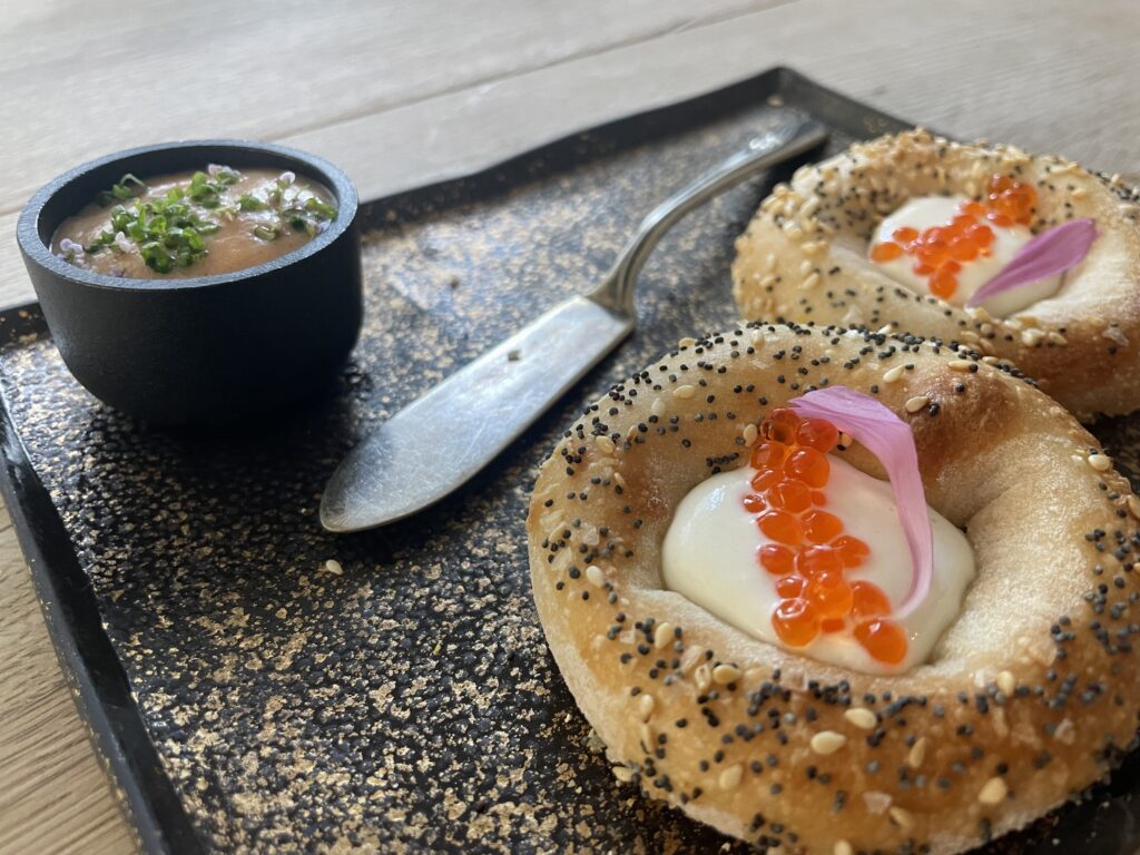 Two bagels on a plate with cream cheese and caviar. 