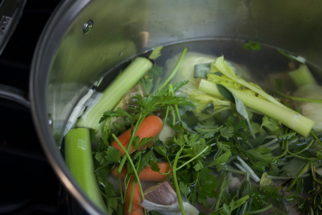 Ingredients for stock in a stainless steel stock pot on the stove.